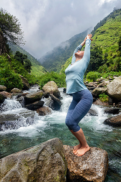 轻的运动健康的妇女瑜伽阿莎娜utkatasana椅子姿势户外热带瀑布站石头上点健康的女人瀑布瑜伽体式图片