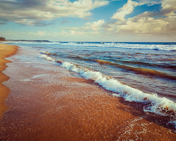 复古效果过滤了潮人风格的形象,涌动沙滩上的热带海滩斯里兰卡Hikkaduwa波浪沙子上涌动图片