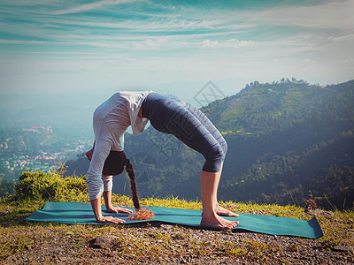 户外瑜伽轻的运动健康的妇女阿什唐加维尼亚萨瑜伽阿萨纳乌尔德瓦达努拉纳向上弓姿势喜马拉雅山山区,上午喜马拉雅山区,印度图片
