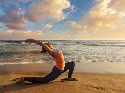 户外瑜伽运动健康的女人练瑜伽安贾尼雅萨纳低新月弓步姿势户外海滩日落运动健康的女人日落的海滩上练瑜伽图片