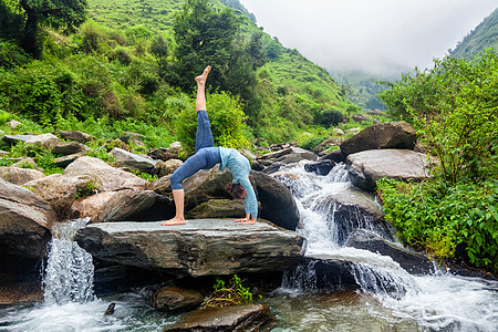瑜伽户外运动瑜伽的女人,如阿莎娜,又名帕达乌尔达瓦,达努拉纳,向上鞠躬,喜马拉雅山瀑布的户外姿势女人瀑布瑜伽体式图片
