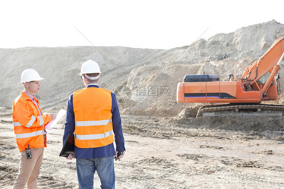 监理人员站建筑工地迎着晴朗的天空图片