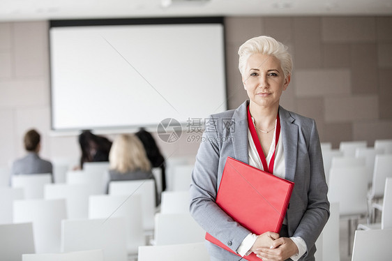 自信的女商人研讨会大厅持文件的肖像图片