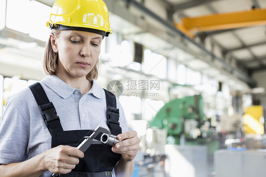 工业上成熟的女职工用卡尺测量金属图片