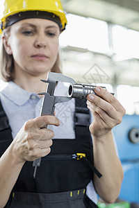 工厂成熟的女职工用卡尺测量金属图片