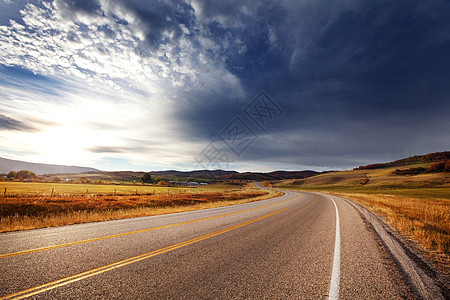 阳光明媚的早晨,乡间道路上五彩缤纷的秋天景象图片