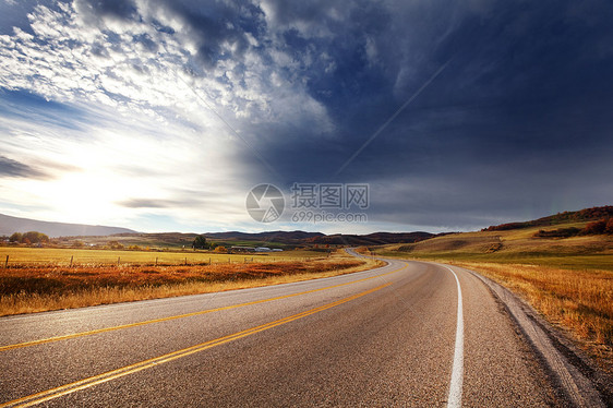 阳光明媚的早晨,乡间道路上五彩缤纷的秋天景象图片