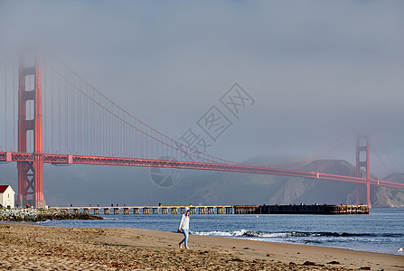 美国加利福尼亚州旧金山金门大桥附近海滩上行走的女人图片
