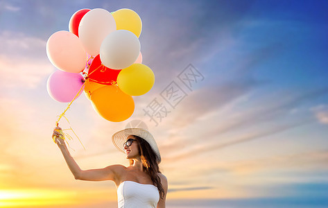 快乐,夏天人的微笑的轻女人戴着太阳镜,日落的天空背景上放着气球戴太阳镜的女人日落的天空上气球图片