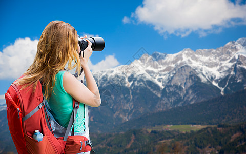 旅行,旅游摄影快乐的轻妇女背包相机拍摄阿尔卑斯山背景女人带着背包相机阿尔卑斯山上图片