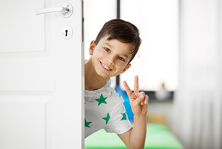 童,乐趣人的快乐的小男孩门后家里表现出平快乐的小男孩门后家里表现出平图片