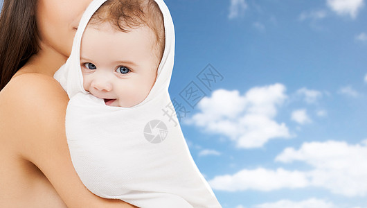 家庭母亲的母亲带着小婴儿裹浴巾上的天空背景妈妈用浴巾天空的背景上图片