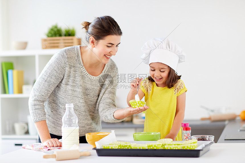 家庭,烹饪,烘焙人们的快乐的母亲与纸杯蛋糕衬里小女儿用勺子倒糊家里厨房松饼快乐的母亲女儿家烤纸杯蛋糕图片