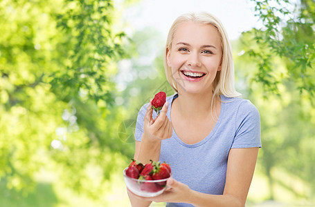 健康的饮食,食物饮食快乐的微笑女人与草莓绿色的自然背景快乐微笑的女人吃草莓图片