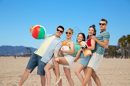 暑假,旅行假期群快乐的微笑朋友戴着太阳镜,带着沙滩球排球毛巾相机加州威尼斯海滩背景上威尼斯海滩上的快乐朋友图片