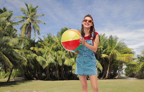休闲暑假微笑的十几岁女孩戴着太阳镜,带球热带海滩背景法属波利尼西亚微笑的十几岁女孩戴着太阳镜带着沙滩球图片
