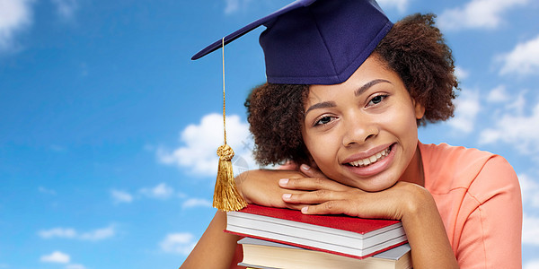 教育,学校,知识毕业快乐微笑的非裔美国研究生女孩灰泥板与书籍梦想蓝天背景用书非洲研究生图片