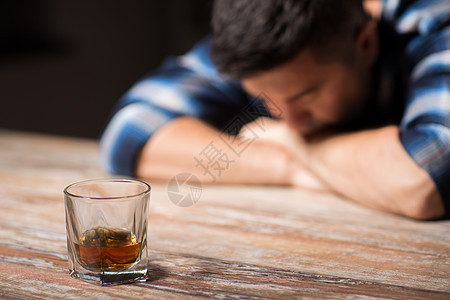 酒精中,酒精成瘾人的男酒精与杯威士忌躺桌子上晚上睡觉晚上桌子上喝了杯酒的醉汉图片
