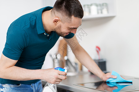清洁,家庭人的男人与喷雾清洁剂擦布炊具家庭厨房家里厨房里抹布清洁炊具的男人图片