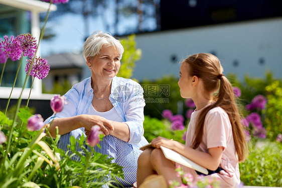 园艺,家庭人的快乐的祖母孙女与笔记本花夏季花园夏天花园的祖母孙女图片