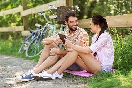 人,技术生活方式的快乐的夫妇与平板电脑电脑自行车夏季公园与平板电脑自行车夏季公园图片