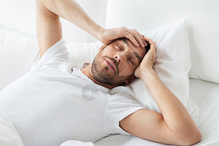人,睡觉时间休息的男人躺床上,患头痛宿醉家卧床的人头痛图片