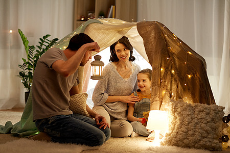 家庭,潮格人的快乐的母亲,父亲带着灯笼,小女儿晚上家里的孩子帐篷里玩快乐的家庭晚上家孩子们的帐篷里玩耍图片