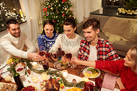 家庭晚餐节日庆祝快乐的朋友家里吃诞晚餐,喝红酒碰杯朋友们庆祝诞节喝酒背景