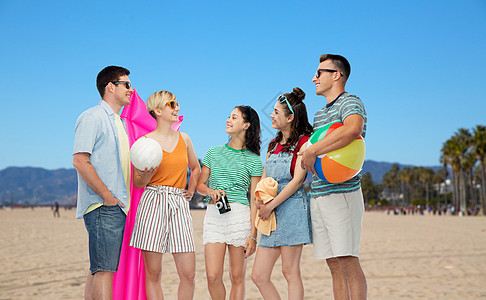 友谊,休闲暑假群快乐的微笑朋友戴着太阳镜,带球,排球,毛巾,相机空气床垫威尼斯海滩背景加州海滩用品的朋友图片