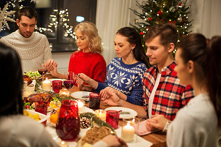 家庭晚餐节日感谢的朋友牵着手祈祷,同时家里吃诞晚餐朋友们回家吃诞晚餐祈祷背景