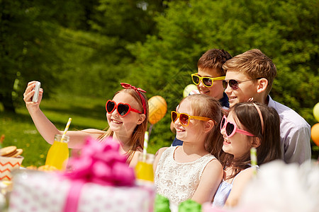 假期,童技术快乐的孩子戴着太阳镜夏天的花园生日聚会上自拍快乐的孩子生日聚会上自拍图片