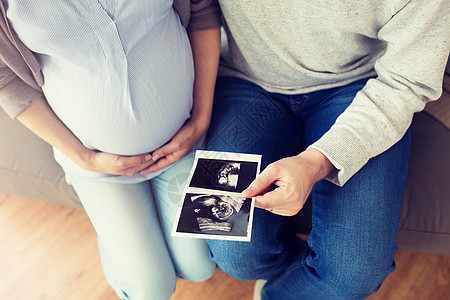 怀孕,家庭人的密切的男人他怀孕的妻子家里看婴儿超声图像夫妇与婴儿超声图像图片