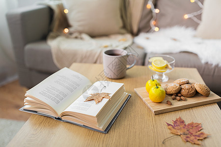 潮湿舒适的家庭书,秋叶,杯柠檬茶,杏仁坚果燕麦饼干桌子上书,柠檬,茶饼干家里的桌子上图片