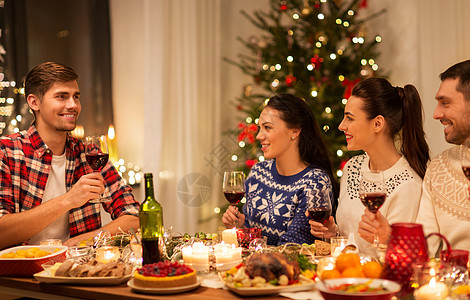 节日庆祝快乐的朋友家里吃诞晚餐喝红酒快乐的朋友诞节聚会上喝红酒图片
