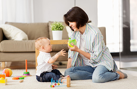家庭,孩子母亲的快乐的母亲与小儿子家里玩发育玩具小杯子快乐的母亲家里给小儿子喝西皮杯图片
