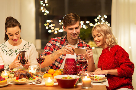 节日庆祝快乐的朋友家里吃诞晚餐,用智能手机拍摄食物快乐的朋友家吃诞晚餐图片