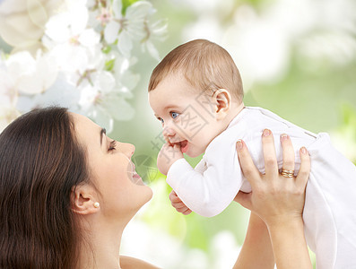 家庭母亲的快乐的微笑轻母亲与小婴儿樱花背景母亲带着孩子樱花背景下图片