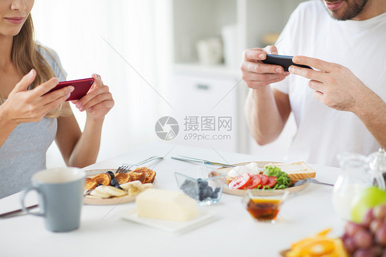 食物技术亲密的夫妇与智能手机家里吃早餐早餐时用智能手机夫妇图片