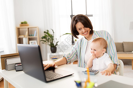 多任务,自由职业母亲的工作的母亲婴儿笔记本电脑家庭办公室家里男婴笔记本电脑工作的母亲图片