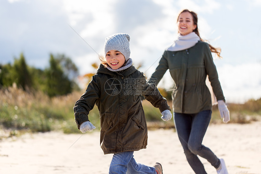 家庭休闲人的快乐的母亲小女儿沿着秋天的海滩跑步幸福的家庭沿着秋天的海滩奔跑图片