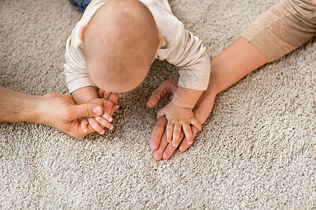 家庭,父母人的亲密的婴儿抱着母亲父亲的手地毯上把孩子关地毯上图片