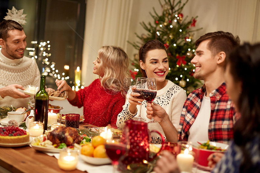 节日庆祝快乐的朋友家里吃诞晚餐,喝红酒碰杯快乐的朋友家吃诞晚餐图片