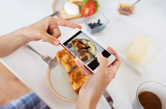 食物,饮食技术手与智能手机拍摄早餐盘子上用智能手机拍照食物的手图片