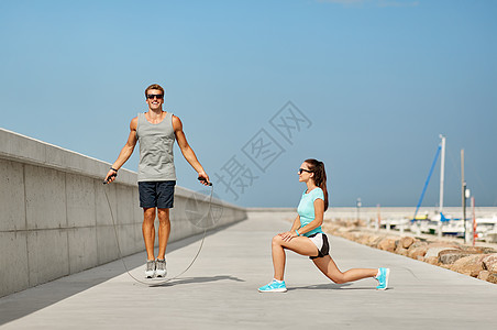 健身,运动生活方式的快乐夫妇伸展跳绳码头上训练前快乐的夫妇训练前码头热身图片