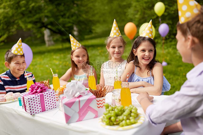 假期,童庆祝快乐的孩子坐桌子上的生日聚会夏季花园快乐的孩子夏季花园的生日聚会上图片