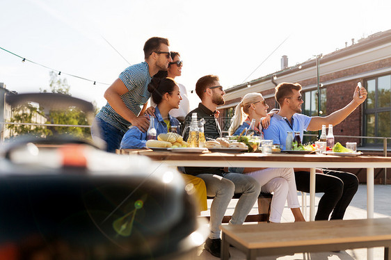 休闲人们的快乐的朋友与饮料屋顶烧烤聚会夏天自拍智能手机快乐的朋友屋顶派上自拍图片