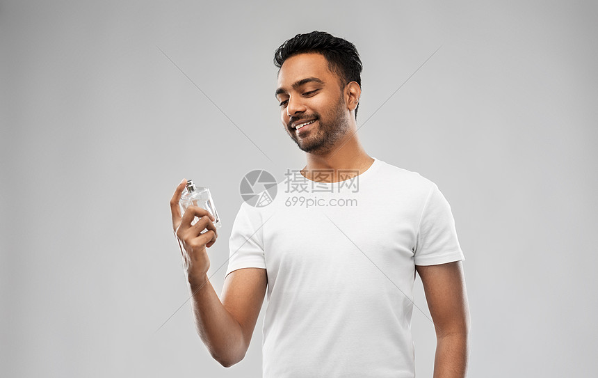 男香水,美容人的快乐微笑的轻印度男子香水灰色背景快乐的印度男人用灰色背景的香水图片