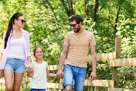 家庭休闲人的快乐的母亲父亲小女儿夏季公园散步快乐的家人夏天的公园散步图片
