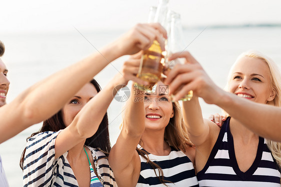 友谊,暑假人们的群穿着条纹衣服的快乐朋友海滩上喝非酒精啤酒快乐的朋友海滩上喝非酒精啤酒图片