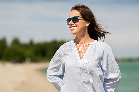 人休闲快乐的微笑女人戴着太阳镜夏天的海滩夏天海滩上戴太阳镜的快乐微笑的女人图片